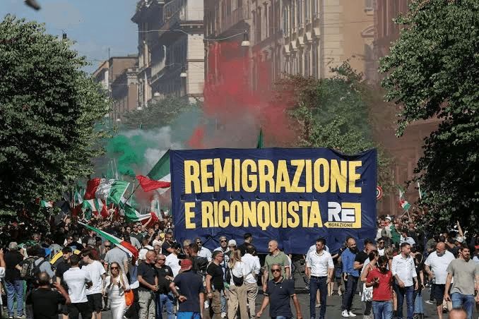 Far-right demonstrators marching with a banner during a rally in RomeNote. From "Far-right demo in Italy calls for 'remigration' of foreigners," by F. Fotia / Reuters, 2026, The Straits Times. (straitstimes.com).